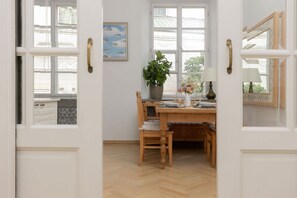 A room with a wooden dining table, chairs, a potted plant, and a window with a view of the outside. - Warsaw | Freta 1 | Spacious Apartment | Old Town | Workspace (Warszawa)