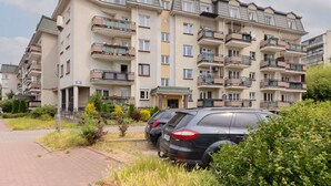Un edificio residencial de varios pisos con balcones, zona de estacionamiento y jardín.