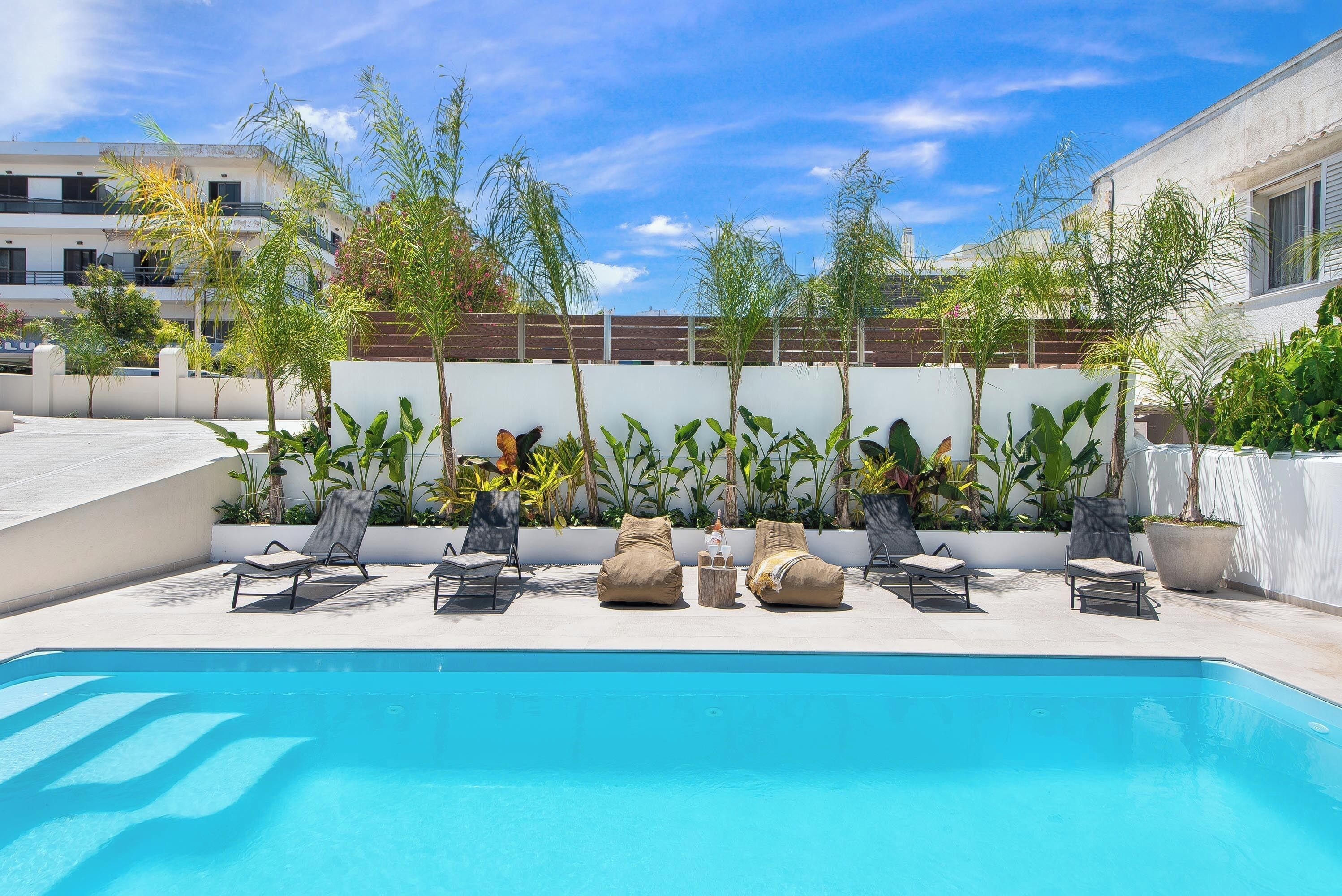 A swimming pool with lounge chairs and potted plants.