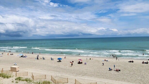 A beach with people, umbrellas, and beach chairs. - Oceanfront Efficiency T401 (Myrtle Beach)