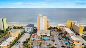 A coastal hotel with a pool, a parking lot, and a view of the beach and ocean. - Oceanfront Efficiency T401 (Myrtle Beach)