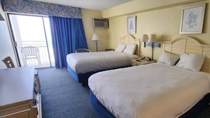 A hotel room with two beds, a desk, a chair, a window with curtains, and a wall-mounted air conditioner. - Oceanfront Efficiency T401 (Myrtle Beach)