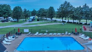 Ein rechteckiger Pool mit einer umlaufenden Sonnenterrasse, Liegestühlen und Sonnenschirmen.