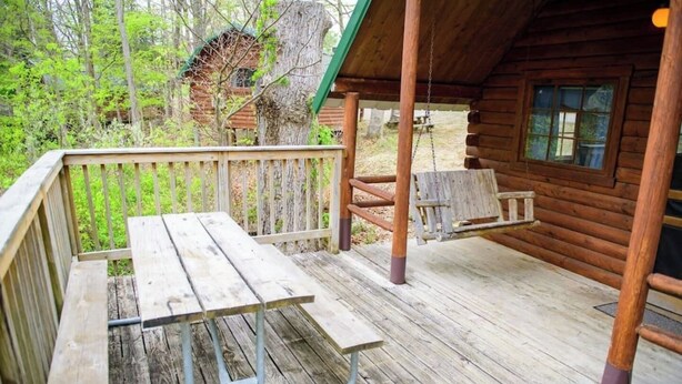 Un pont de fusta amb taula de pícnic i bancs, envoltat d'una tanca de fusta i arbres.