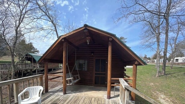 A wooden cabin with a porch, a swing, and a white plastic chair. - Secluded Rustic Cabin with Views (Bloomington)