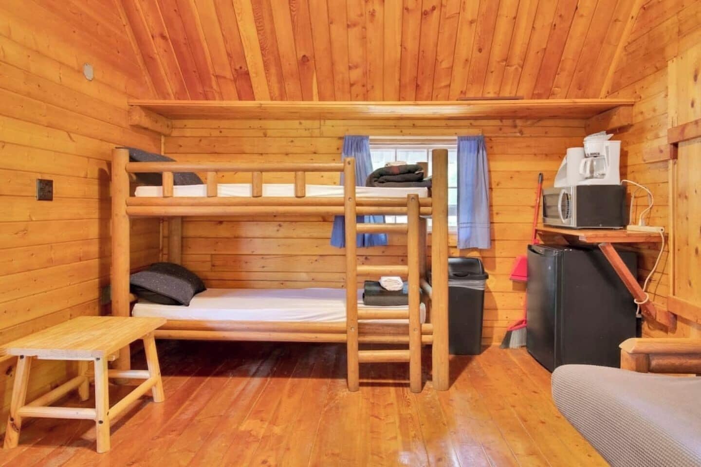 A compact cabin with bunk beds, a small table, a TV, and a refrigerator.