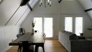 A dining area with a long table and chairs, a gray sofa, and a chandelier. - Stunning Aframe Cabin with Deck (Bloomington)
