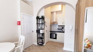 A compact kitchen with white cabinets, a black countertop, and a herringbone-patterned floor. - Lovely Renovated Large Spacious Georgian Studio (Dublin 1)