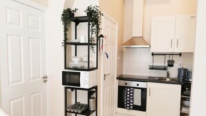 A compact kitchen with white cabinets, a black microwave, and a stainless steel sink. - Lovely Renovated Large Spacious Georgian Studio (Dublin 1)