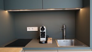 Ett modernt kök med en inbyggd induktionshäll, en diskho i rostfritt stål och en kompakt köksfläkt.