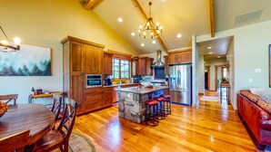 A spacious kitchen with wooden cabinets, a central island with stools, and a dining area with a wooden table and chairs.
