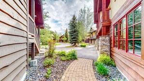 A residential building with a stone facade, wooden siding, and a paved driveway.