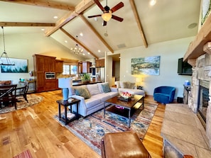 A spacious living room with a fireplace, a dining area, and a kitchen with wooden cabinets.