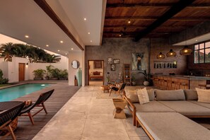 A spacious indoor area with a pool, seating, and a bar area.