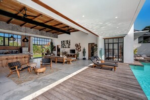 A modern interior with a kitchen, seating area, and a poolside lounge. - Villa Maje by Alfred in Bali (Seminyak)