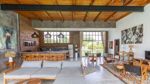 Uma sala ampla com um sofá grande, mesa de centro de madeira e uma área de cozinha com balcão.