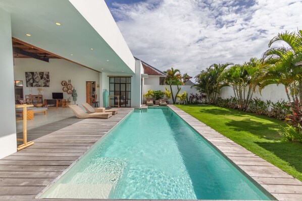 A modern house with a swimming pool, wooden deck, and a well-maintained lawn. - Villa Maje by Alfred in Bali (Seminyak)