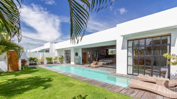 Uma casa moderna com piscina, um pátio e uma grande porta de vidro que dá para uma sala de estar.