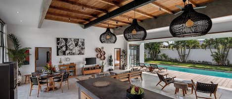 A spacious living area with a pool, wooden ceiling beams, and modern furniture.