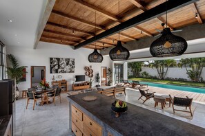 Amplia sala de estar con piscina, vigas de madera en el techo y muebles modernos.