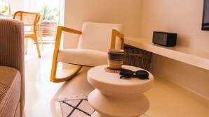 A modern living room with a rocking chair, a small round table with sunglasses, and a shelf with a speaker. - Vacation apartment Matimar, Costa Calma, terrace, WiFi (Costa Calma)