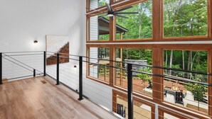Un interior espaiós amb un sostre alt i grans finestres que donen vista a una zona exterior enjardinada.