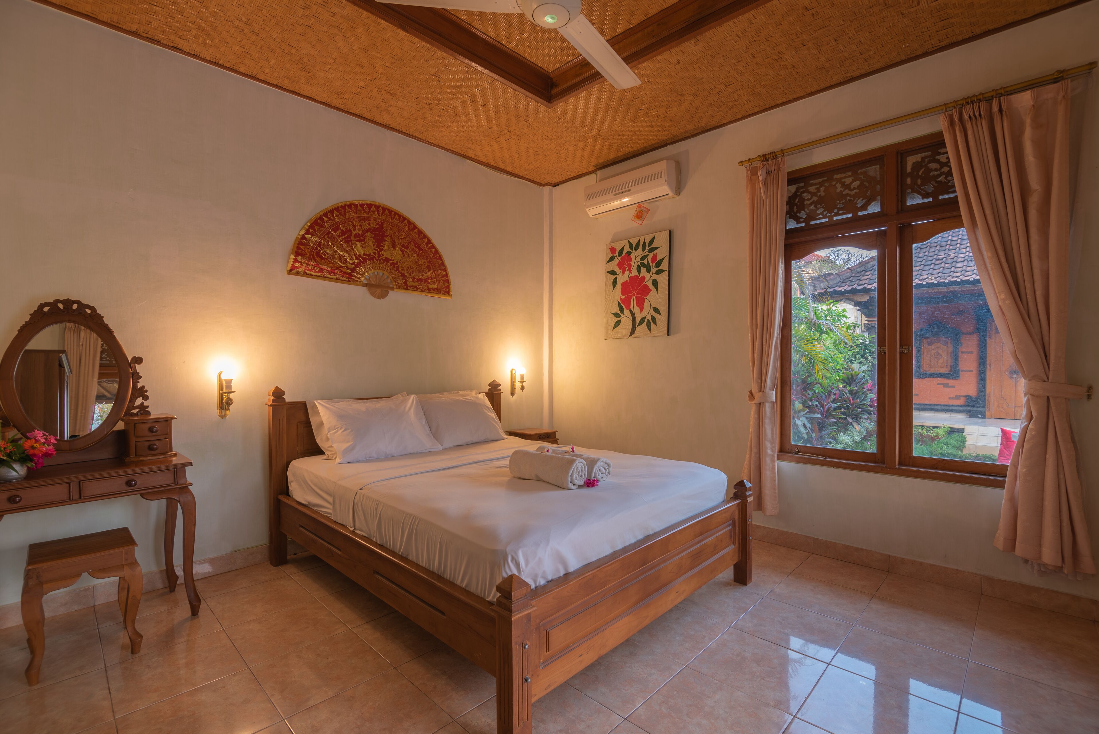 A neatly arranged bedroom with a wooden bed, a bedside table with a mirror, and a window with curtains.