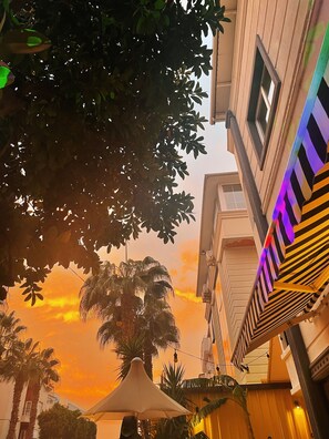 A building with a modern facade, a balcony with striped awnings, and a sunset sky.