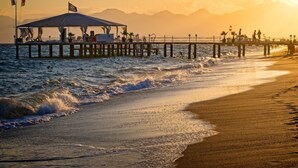 A pier extending into the sea with a covered seating area and flags. - Cabbana Hotel Lara (Antalya)