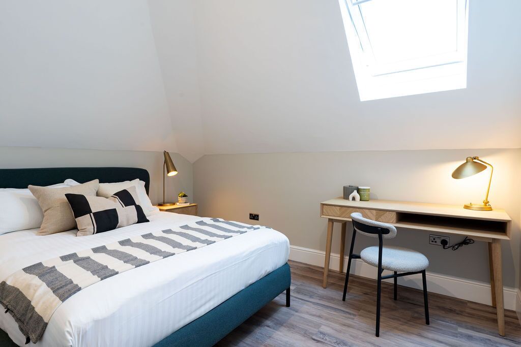 A bedroom with a bed, a desk, and a chair.