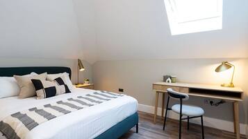 A bedroom with a bed, a desk, and a chair.