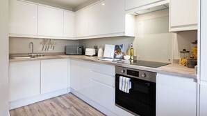 Eine moderne Küche mit weißen Schränken, einer eingebauten Mikrowelle, einem Toaster und einem Geschirrspüler.