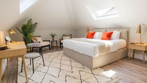 Ein Schlafzimmer mit Bett, Schreibtisch, Stuhl, kleinem Tisch und Topfpflanze.