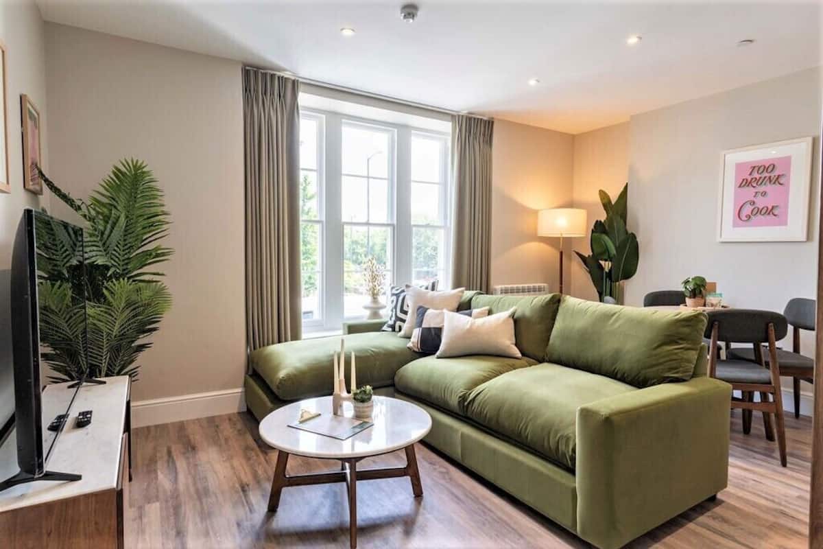 Een woonkamer met een groene bank, een ronde salontafel en een televisie op een standaard.