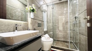 Un baño moderno con un lavamanos grande, espejo y cabina de ducha de vidrio.