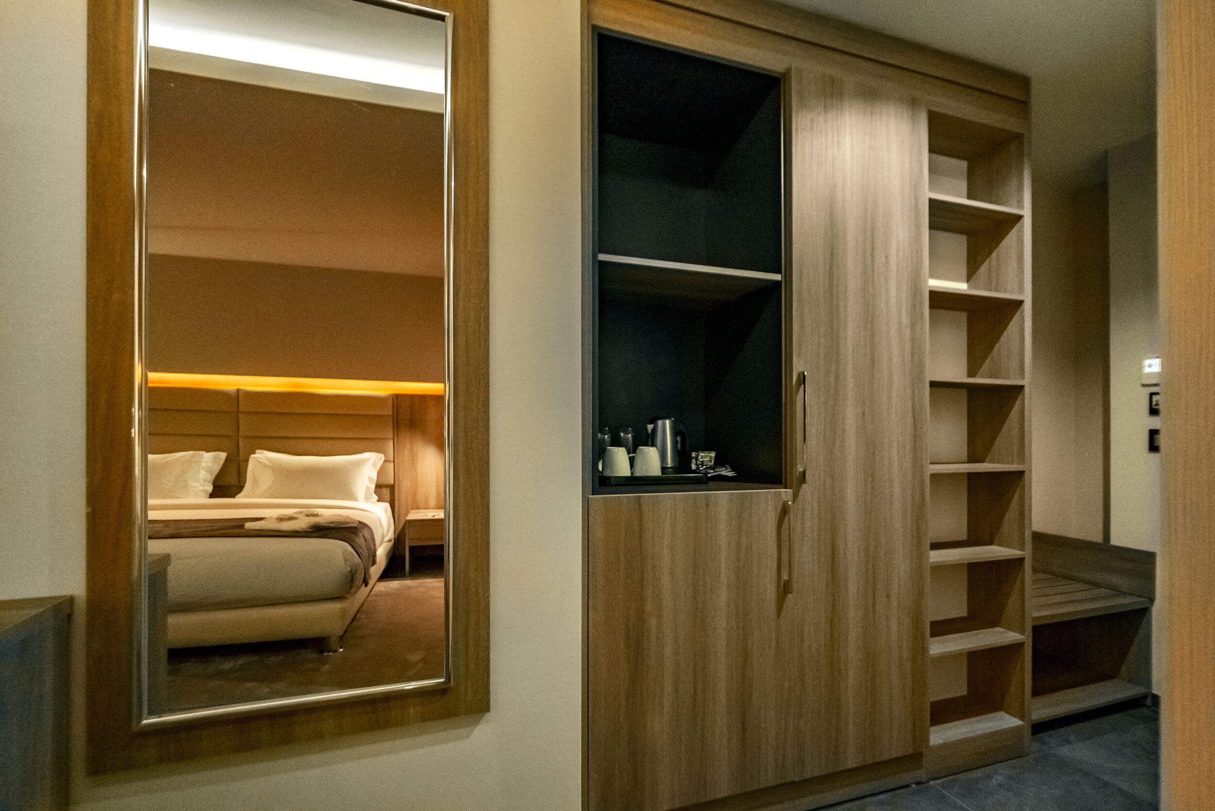Quarto com um espelho grande, uma cama e um guarda-roupa com prateleiras.