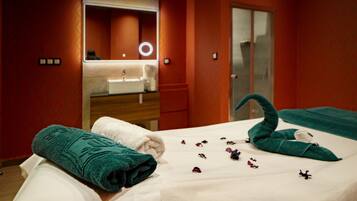 A hotel room with a bed, a bathroom with a mirror, and a door.