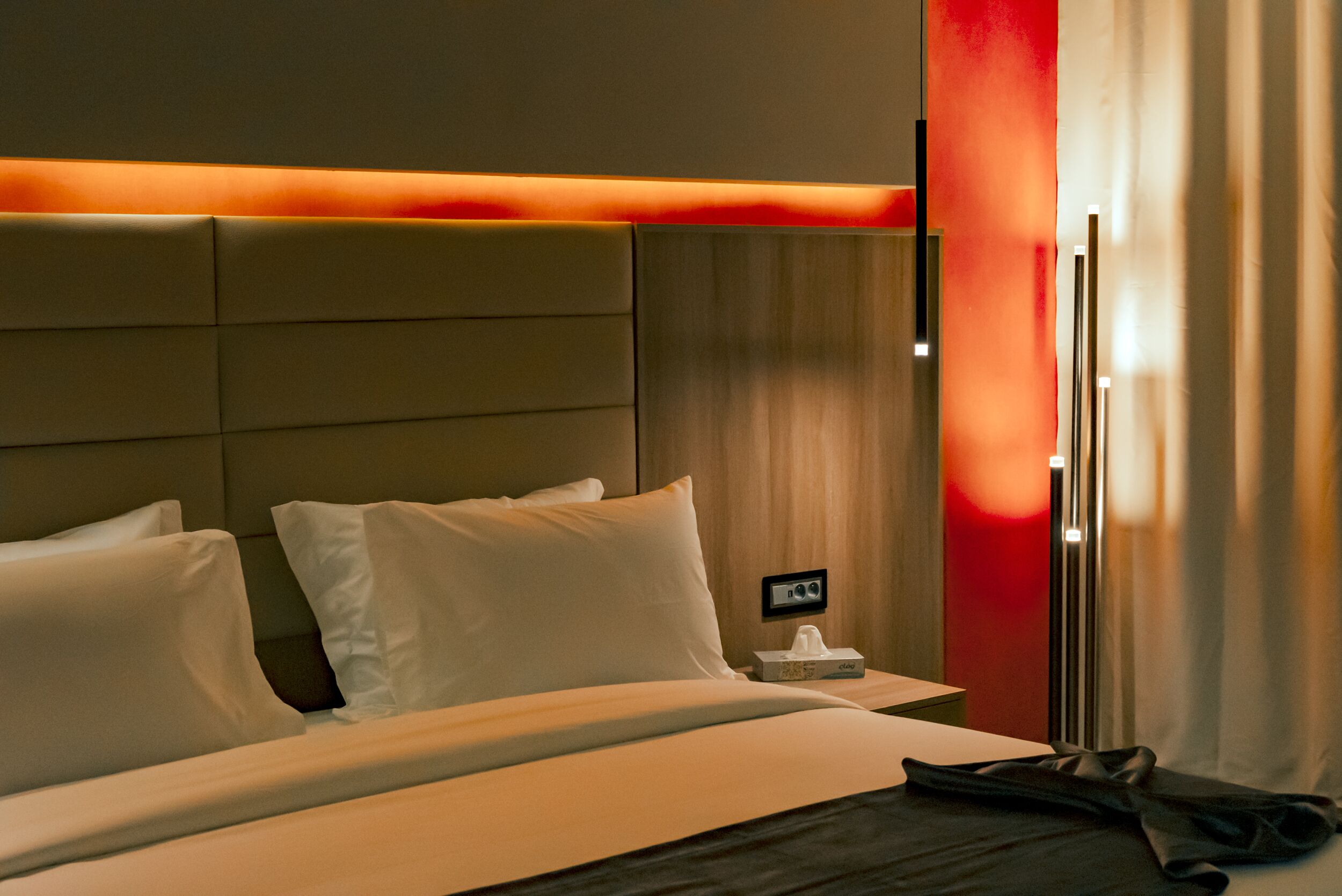 Una habitación de hotel con una cama, una mesita de noche y otra mesa auxiliar.