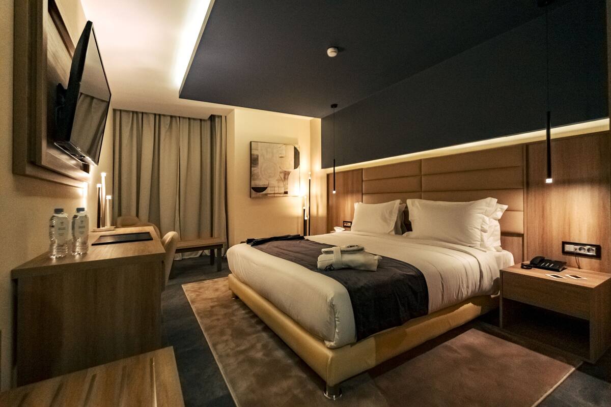 A modern hotel room with a large bed, a desk, and a television.