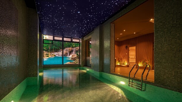A serene indoor pool area with a starry ceiling, a view of a natural landscape through large windows, and a warm, inviting interior. - AD HOTEL HYDRA (Algiers)