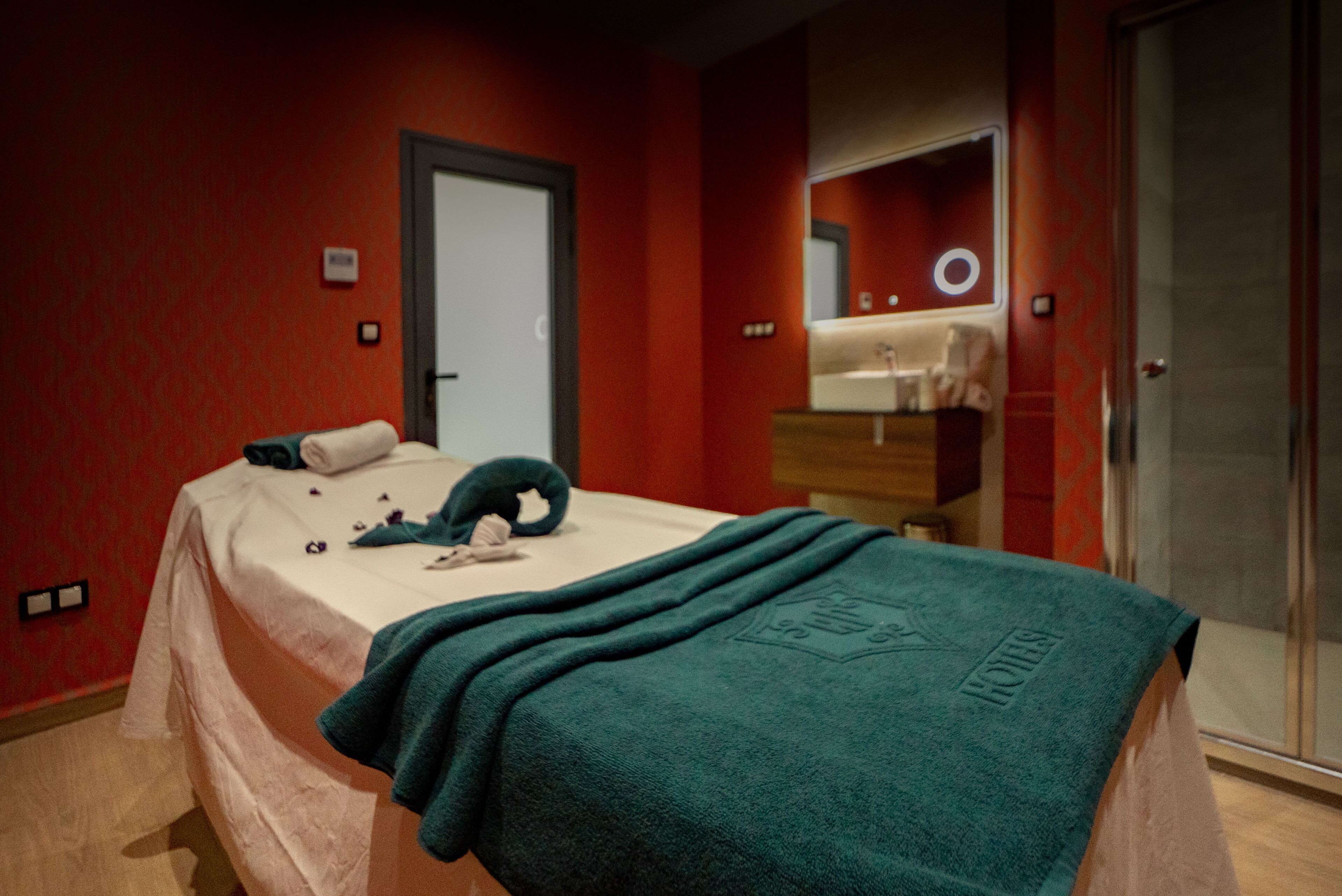 Una habitación de hotel con cama, espejo de baño y puerta.