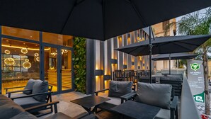 An outdoor seating area with modern furniture, including sofas and tables, under large umbrellas. - AD HOTEL HYDRA (Algiers)