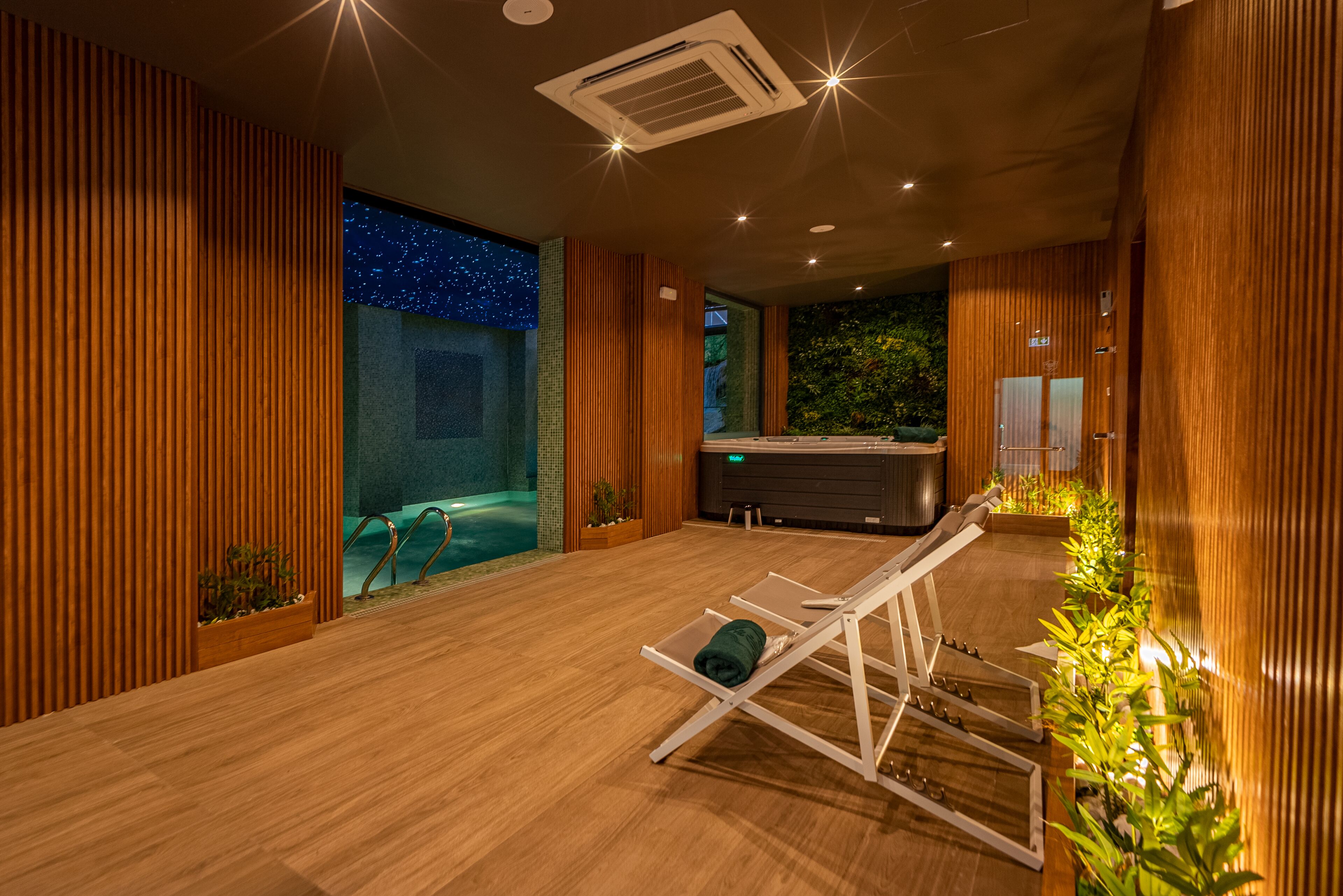 A spa room with wooden paneling, a pool, and a relaxation area with a chair.