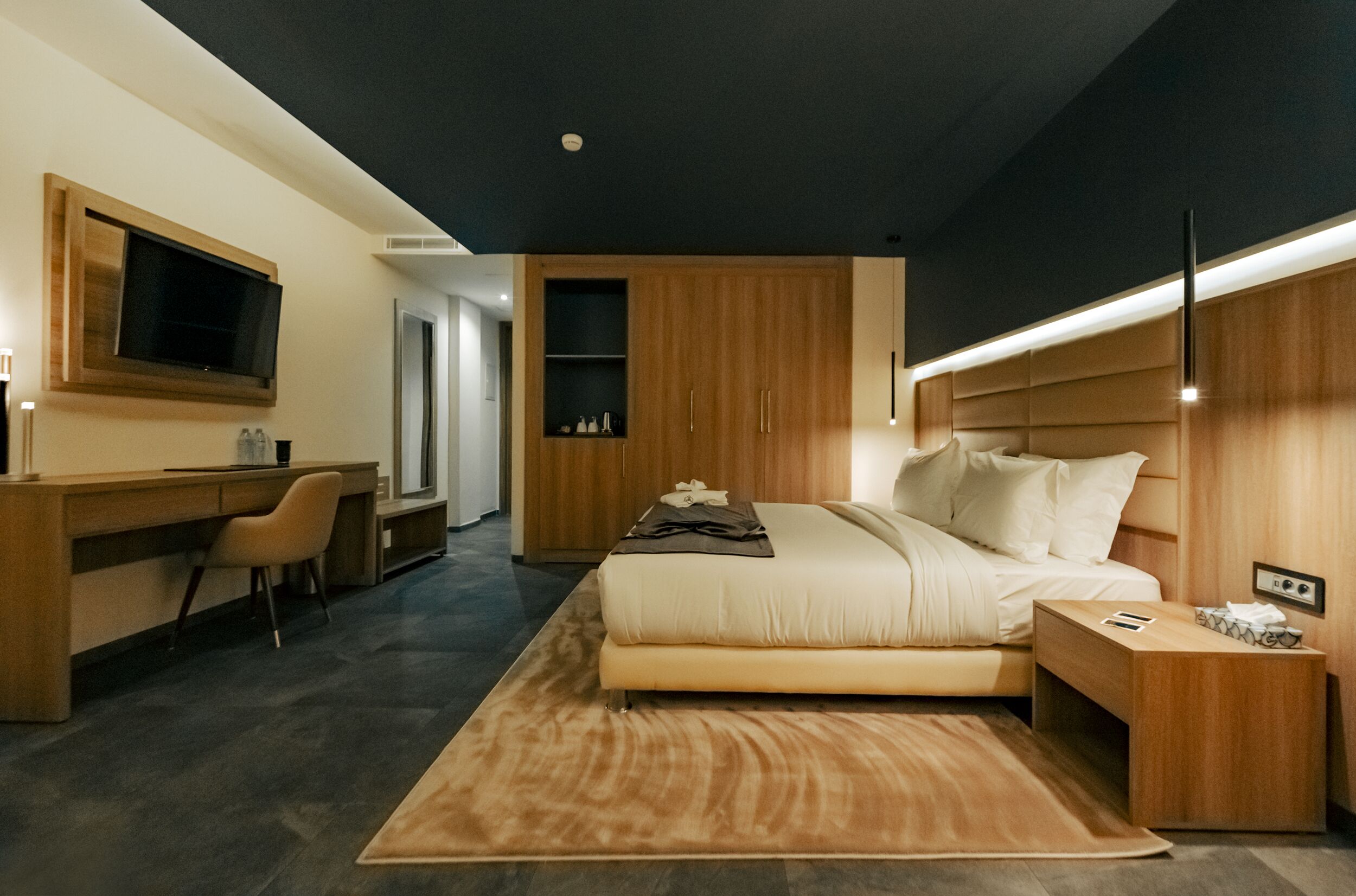 Un dormitorio moderno con cama, mesita de noche y un espacio de escritorio con silla.