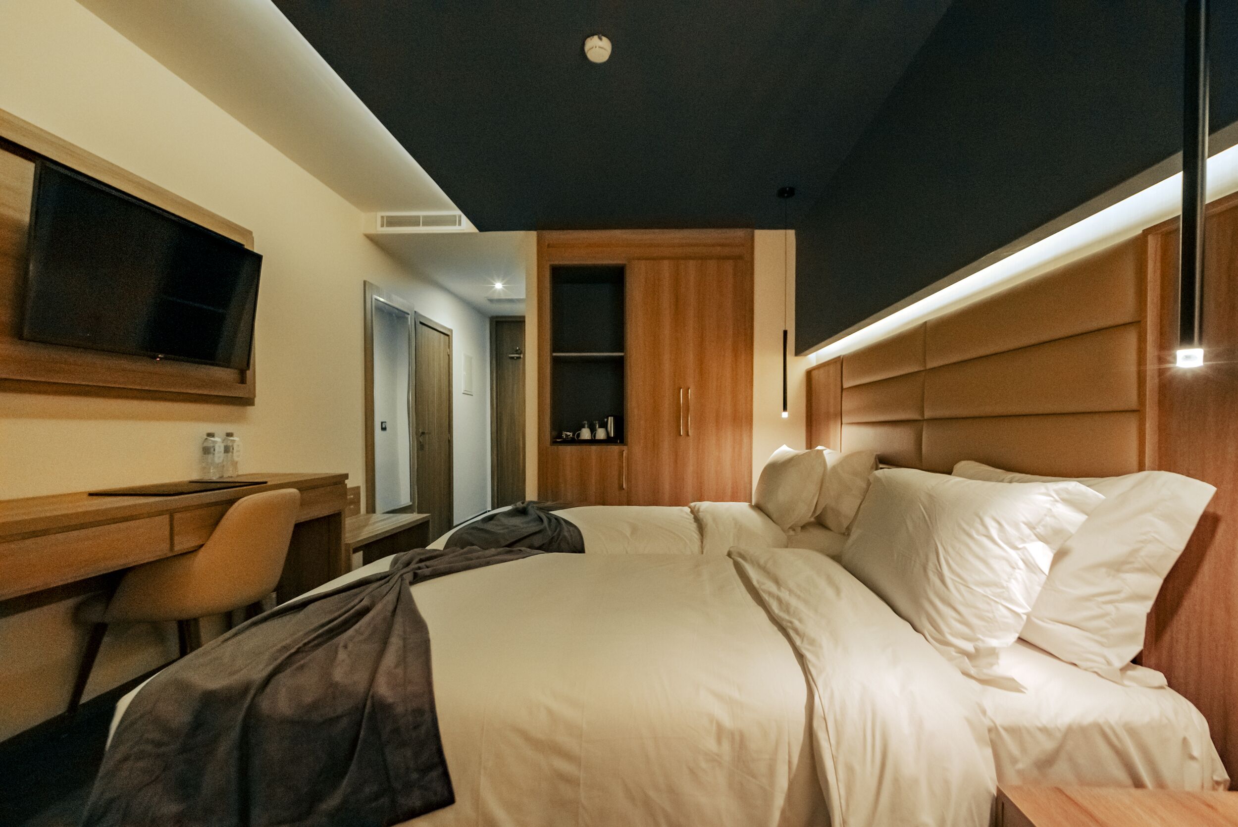 A modern hotel room with a bed, a desk, and a television.