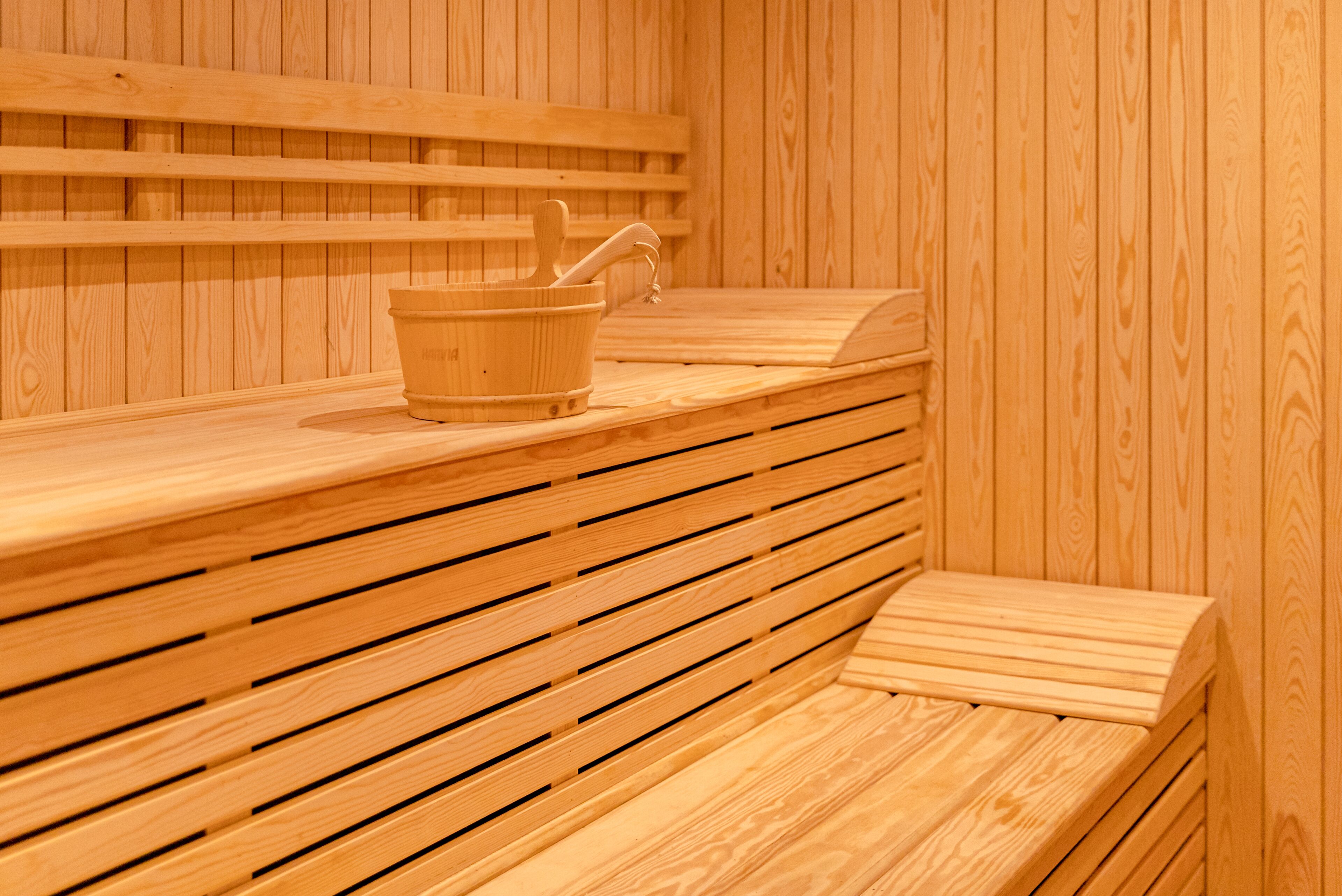 Eine Saunabank aus Holz mit einem Holzeimer und einem Wasserhahn.