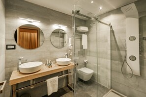 A modern bathroom with two sinks, a toilet, and a glass-enclosed shower.