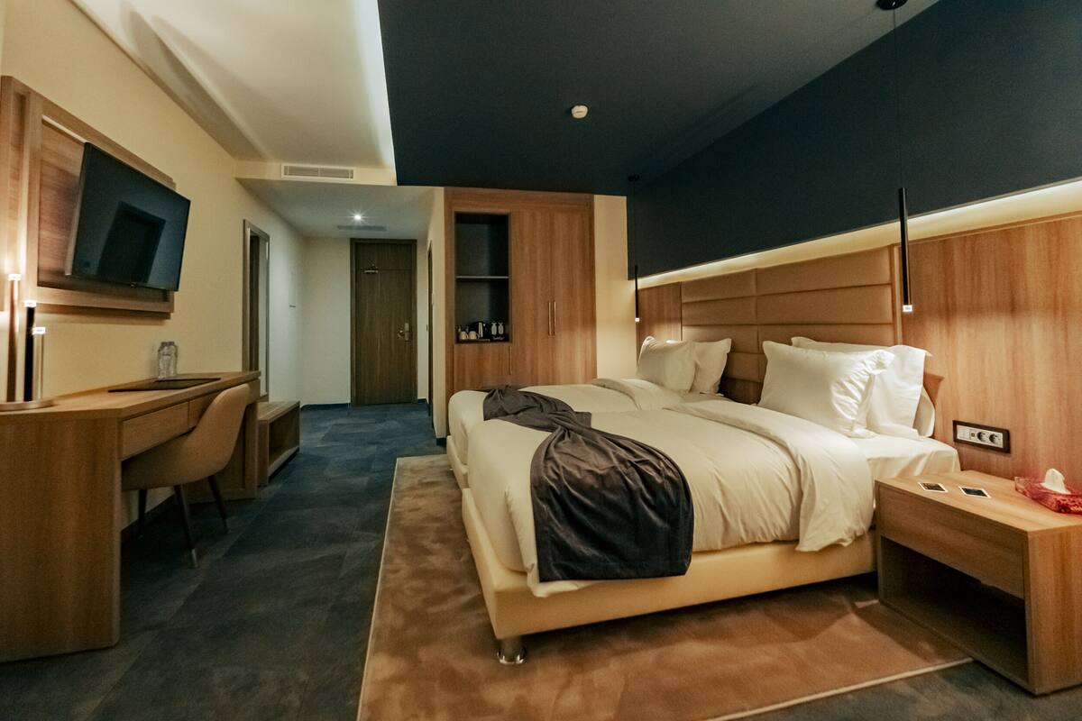 A modern hotel room with a large bed, a desk, and a television.