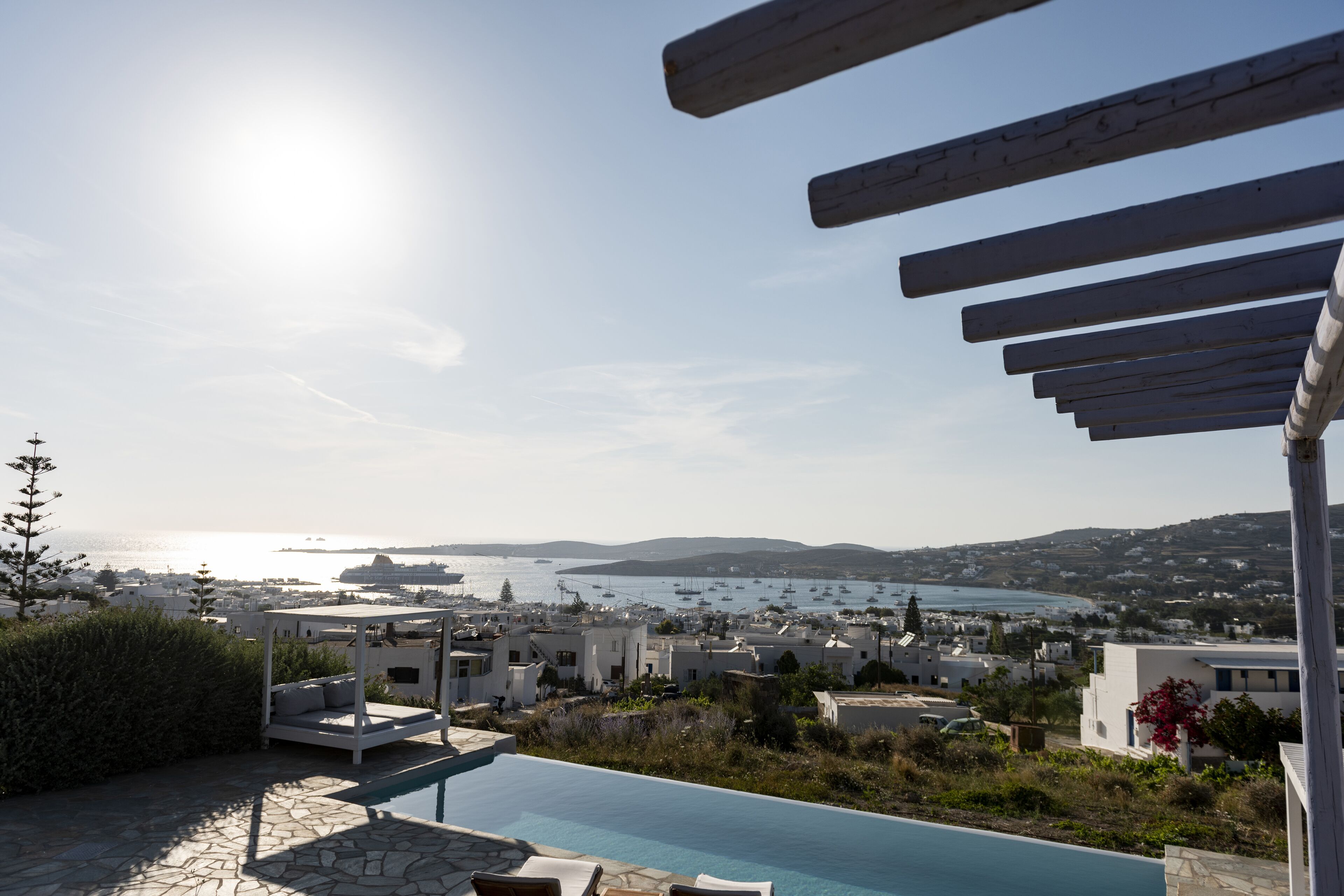 A poolside view overlooking a coastal town with a clear sky and a view of the sea.