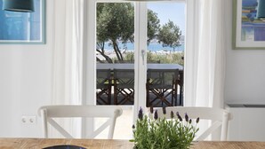 Un comedor con mesa de madera, planta en maceta, cuenco decorativo y lámparas colgantes.
